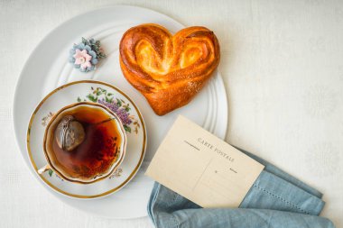 Fincan çay ve kartpostal beyaz masa üstü görünümü ile tatlı çörek