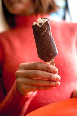 Bitten chocolate covered popsicle in the woman` s hand clipart