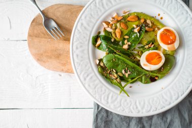 Badem, yumurta ve Beyaz ahşap masa üstü görünümünde ıspanak salatası