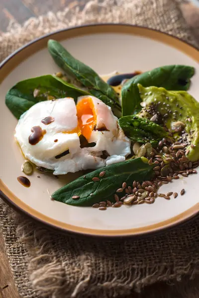 Poached egg with avocado cream sauce and spinach on the ceramic plate  vertical — Stock Photo, Image