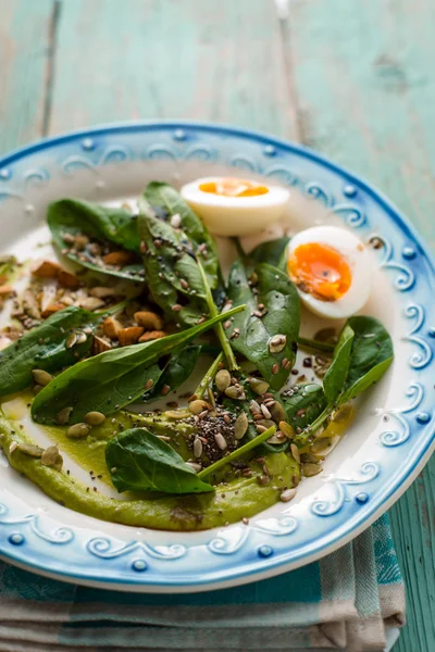 Spinach with avocado sauce and eggs on the light blue background vertical — Stock Photo, Image