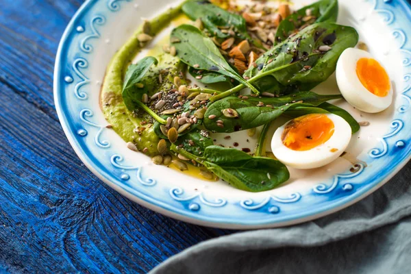 Spinach with avocado sauce and eggs on the bright blue background horizontal — Stock Photo, Image