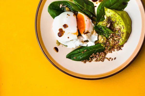 Poached egg with avocado cream and spinach on the yellow background top view — Stock Photo, Image