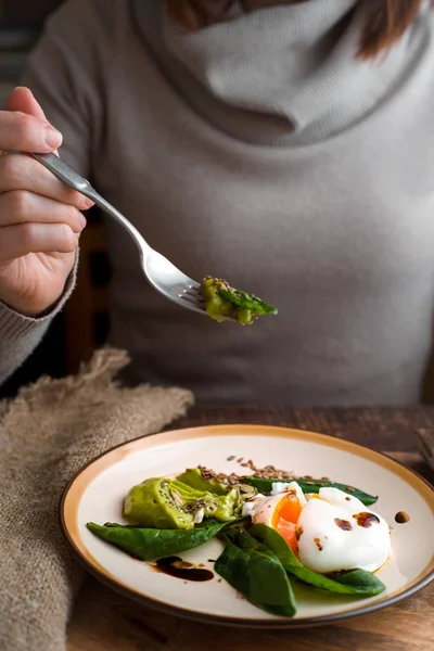 Woman eating poached egg with avocado cream vertical — Stock Photo, Image