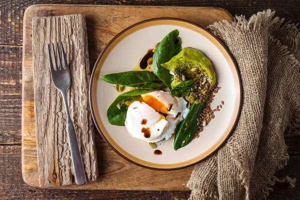 Gepocheerd ei met avocado crème en spinazie op de oude houten tafel — Stockfoto