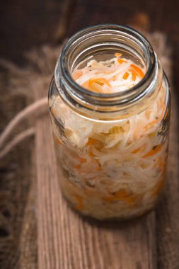 Ahşap bir masa üzerinde bir cam kavanoza lahana turşusu