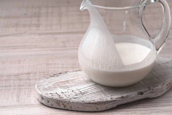 Jug with kefir on a white stand on a wooden table — Stock Photo, Image