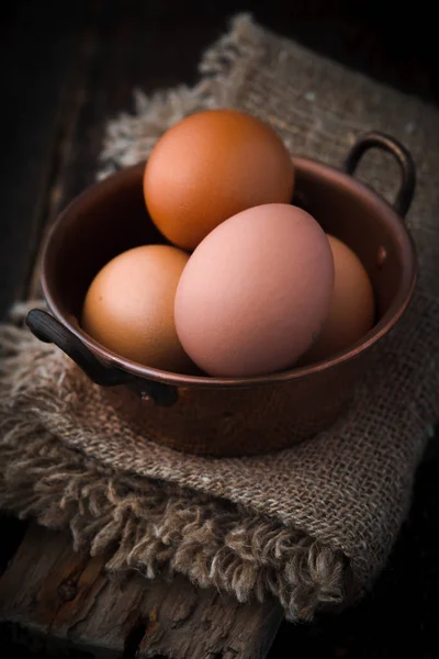 Huevos de pollo en la olla de cobre en la mesa de madera vertical — Foto de Stock