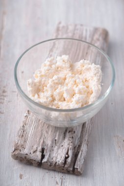 Beyaz ahşap masa üzerinde cam kase süzme peynir 