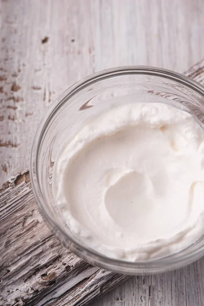 Crema agria en el cuenco de vidrio en la vista superior de fondo de madera blanca — Foto de Stock