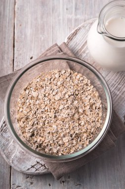 Beyaz ahşap masa üstü görüntüsü üzerinde cam kapta çiğ yulaf gevreği