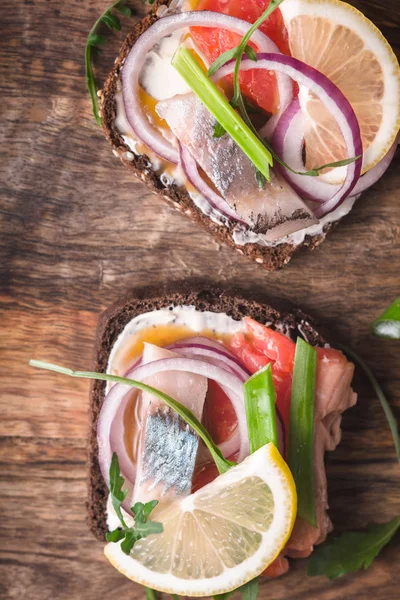 Нарізаний хліб з копченим лососем, оселедцем, лимоном і руколою крупним планом — стокове фото