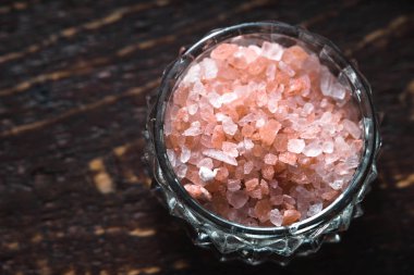 Sağdaki ahşap bir masa üzerinde bir kasede pembe tuz