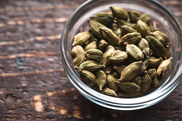 Cordamom seeds in a bowl on the table to the right — Stock Photo, Image