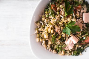 Tavuk ve hakkı olan beyaz bir tablo üzerinde bir kase içinde fasulye salatası