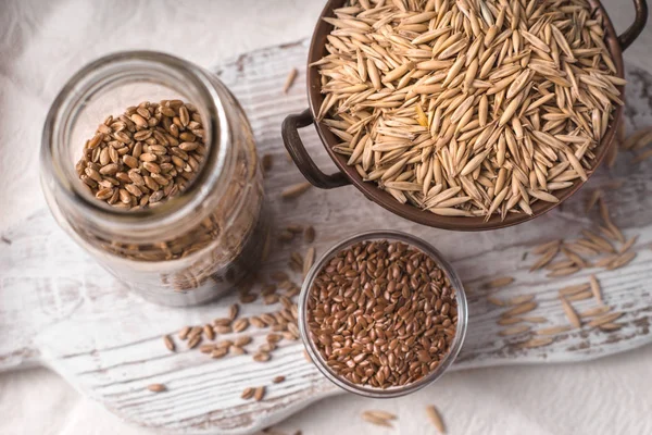 Flax seeds, oats and wheat in the banks on the table — Stock Photo, Image