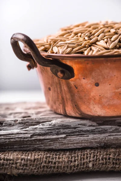 Oats in a copper bowl on a wooden stand on the napkin — Stock Photo, Image