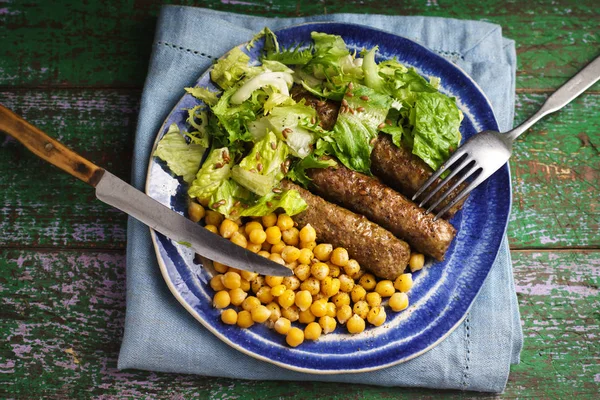 Chevanchichi avec laitue et pois chiches sur une assiette et couteau, fourchette — Photo