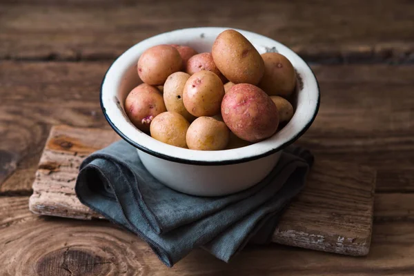 Surowe ziemniaki metalowe miski na drewnianym stole — Zdjęcie stockowe