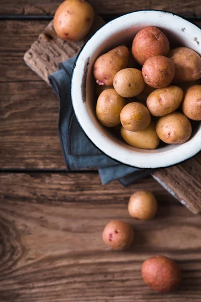Surowe ziemniaki metalowe miski na drewniany blat Zobacz — Zdjęcie stockowe