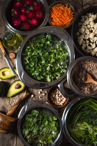 Vegetables, chickpeas, herbs in bowls in the water, half an avocado on the table — Stock Photo, Image