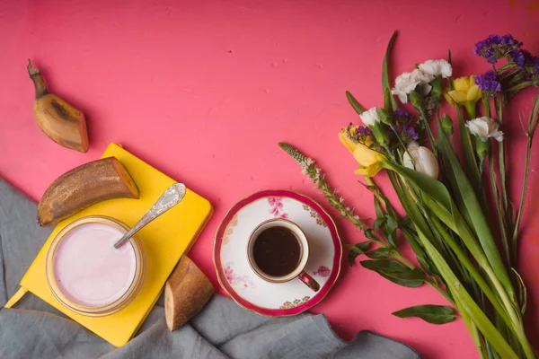 Buquê de flores, iogurte, xícara de café em uma mesa rosa — Fotografia de Stock