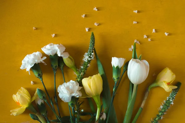 Tulipas e cravos em uma mesa amarela — Fotografia de Stock