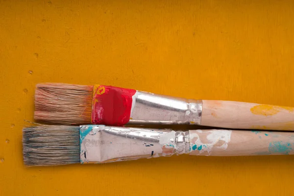 Dois pincéis de tinta em uma mesa amarela espaço livre — Fotografia de Stock