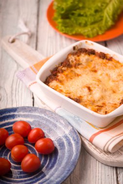 Ev yapımı et lazanya ve domates, marul ahşap stand