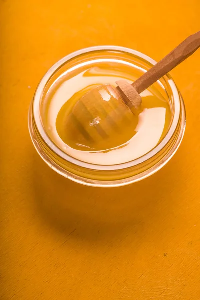 Miel sur le bol en verre sur le fond jaune vertical — Photo