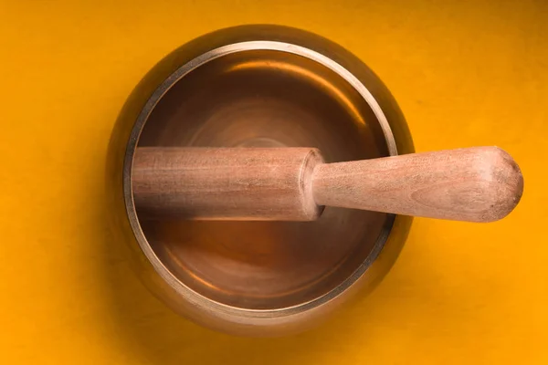 Metal bowl with a wooden stick on a yellow table — Stock Photo, Image