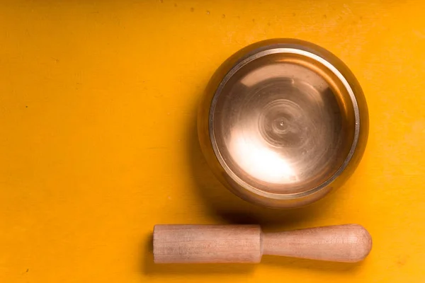 Металлическая чаша с деревянной палкой на желтом столе справа — стоковое фото