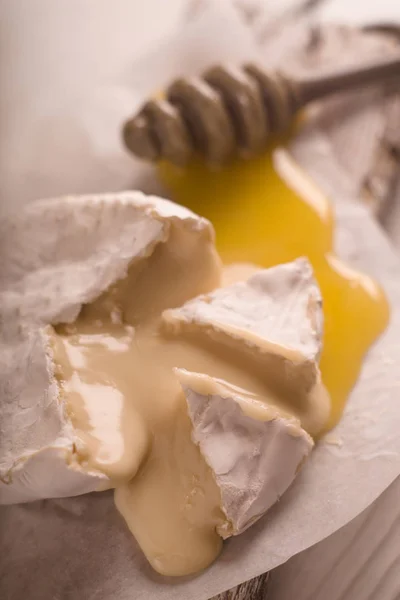 Brie cheese, slices, honey on parchment blur — Stock Photo, Image