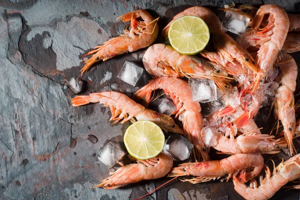 Prawns with lemon and ice cube on the stone background top view — Stock Photo, Image