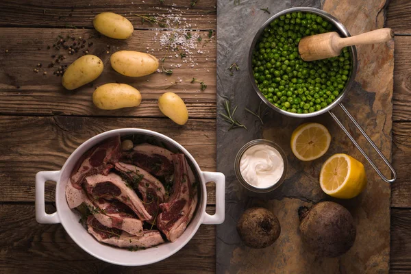 Ribben van lamsvlees, aardappelen, citroen, erwten in een bolletje — Stockfoto