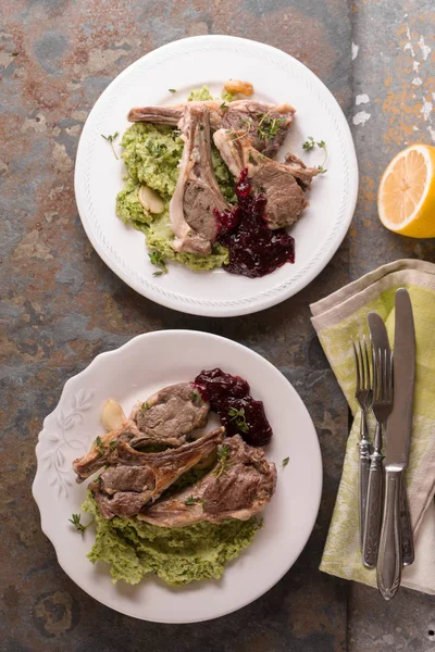 Serving of lamb ribs grilled, mashed potatoes, beetroot sauce, lemon, plates, napkin on the table — Stock Photo, Image