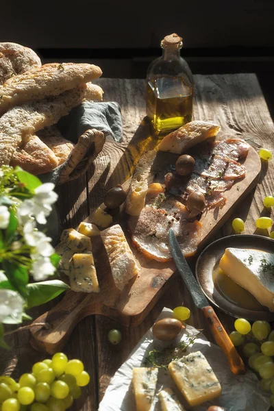 自家製のパン、チーズ、オリーブ、ハモン、古いボードの花 — ストック写真