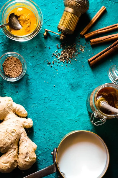 Ingredientes para el café con leche de cúrcuma sobre fondo cian vertical — Foto de Stock