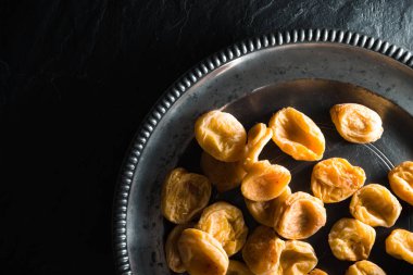 Sağ tarafta taş bir tablo ile bir teneke tabakta Kuru Kayısı