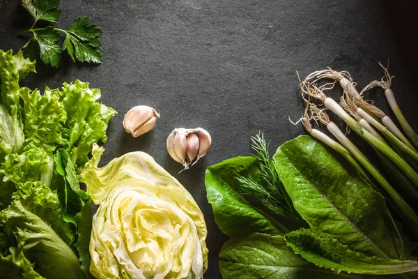 Lechuga iceberg, cebollas verdes y espinacas y ajo sobre pizarra gris —  Fotos de Stock