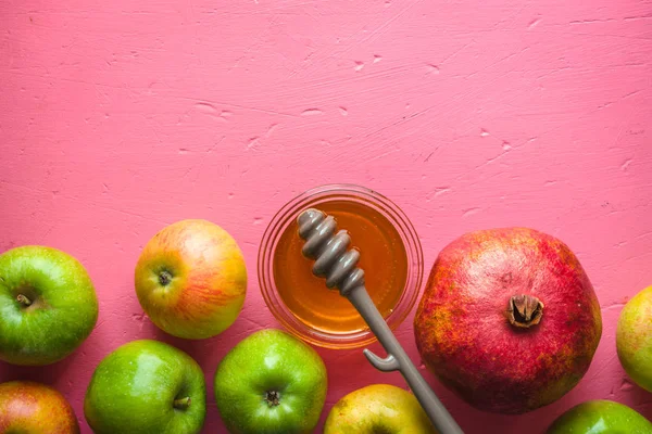 半框架的苹果、 石榴、 蜂蜜为犹太新年粉红色的桌子上 — 图库照片
