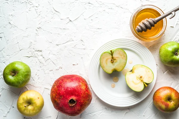 上板、 石榴和蜂蜜在白色桌子上的苹果的两半 — 图库照片