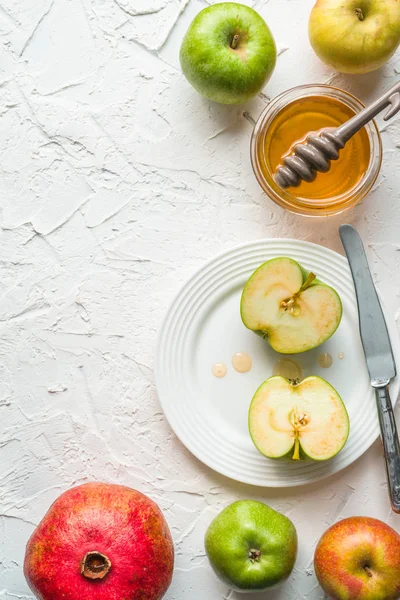 Halvorna av äpplen i honung på en keramisk platta, granatäpple på ett vitt bord — Stockfoto