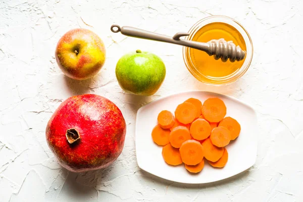石榴、 苹果、 胡萝卜和蜂蜜在表的中心白色 — 图库照片