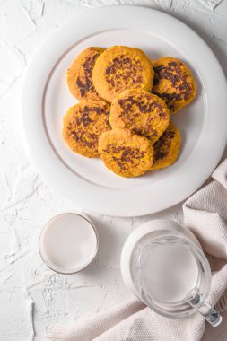 Kupası ve kenevir süt ile sürahi, balkabağı beyaz masada krep