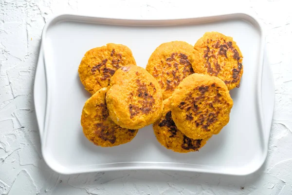 Frittelle di zucca vegetariane su un piatto bianco su uno sfondo bianco — Foto Stock