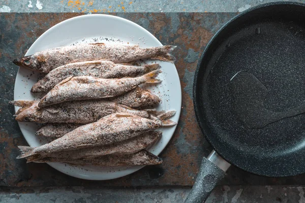 Риба на тарілці, сковорідка на сіро-бежевому фоні — стокове фото