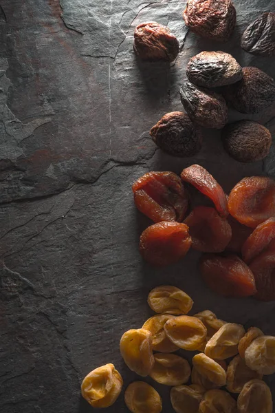 Albicocche secche marroni, arancioni, gialle su una pietra grigia — Foto Stock