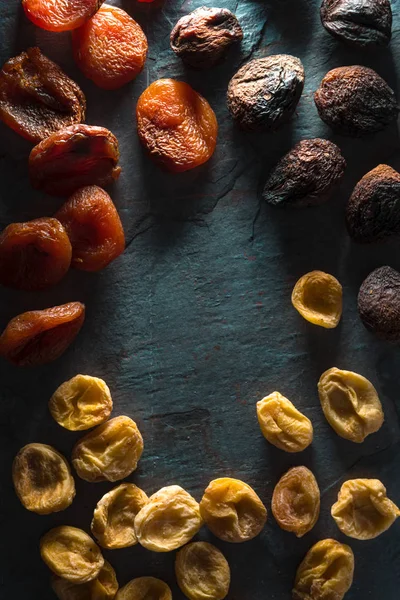Frame of brown, orange, yellow dried apricots on a gray stone — Stock Photo, Image