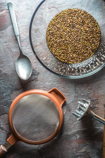 Bol en verre avec graines de cannabis, tamis et mélangeur sur pierre — Photo